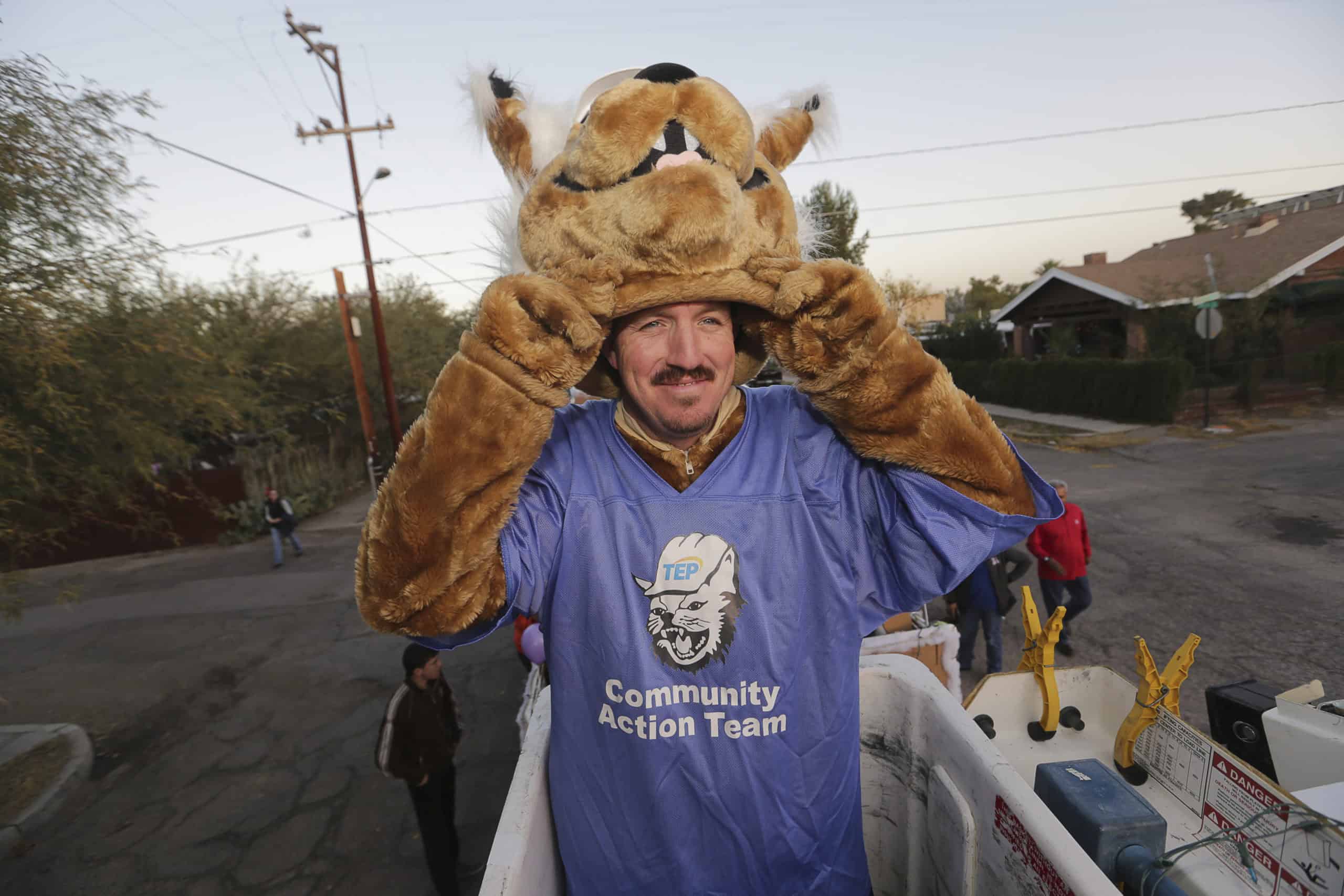 Volunteer managing community events wearing mascot headgear.