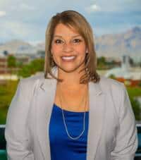 Compassionate woman smiling with mountains and cityscape background, promoting volunteer management.